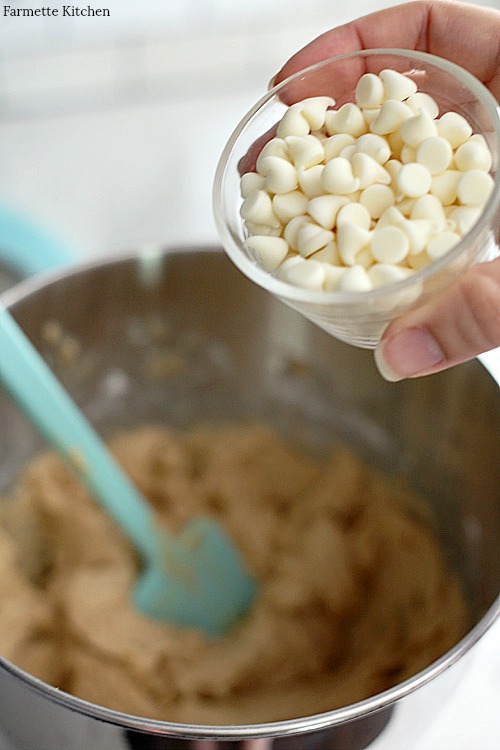 adding a small bowl of white chocolate chips to blondie batter