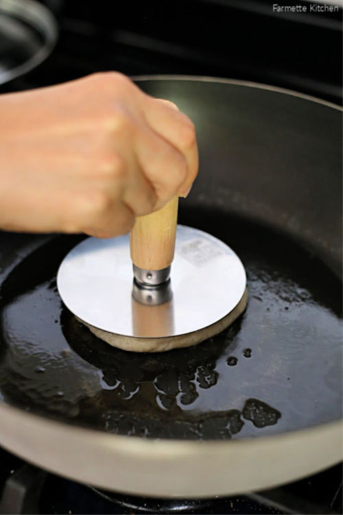 using a hotteok press to press down a Korean pancake
