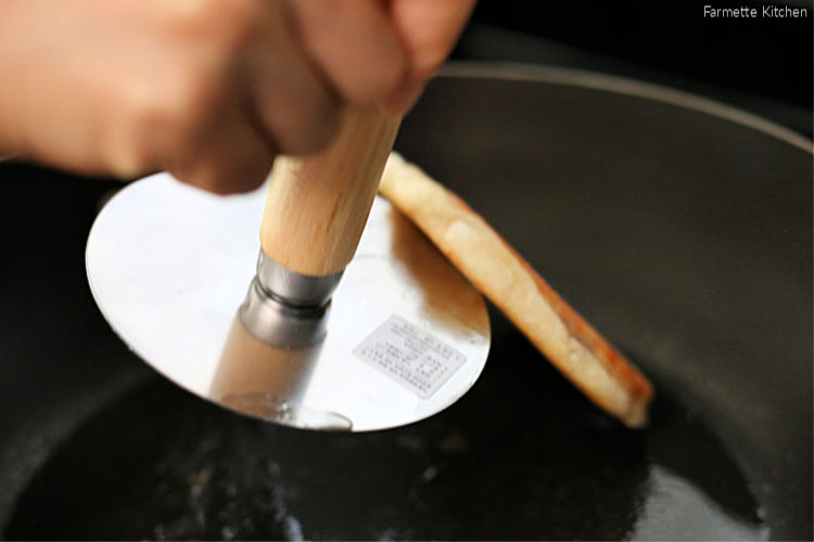 using a hotteok press to flip a Korean pancake