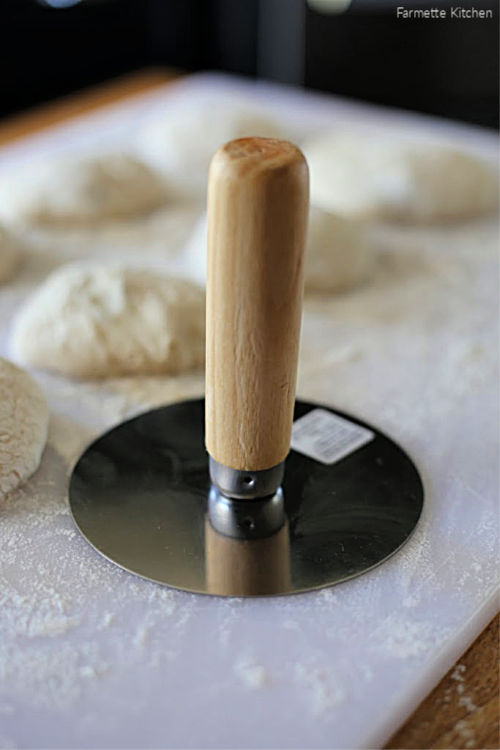 a hotteok press next to hotteok dough on a cutting board