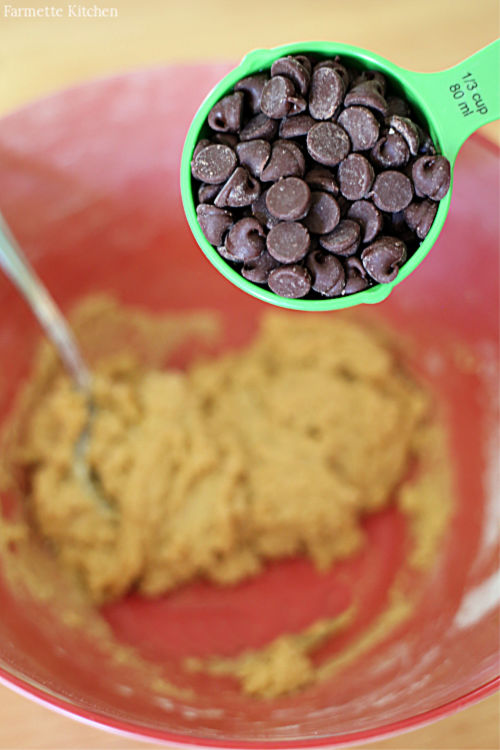 chocolate chips being added to cookie dough