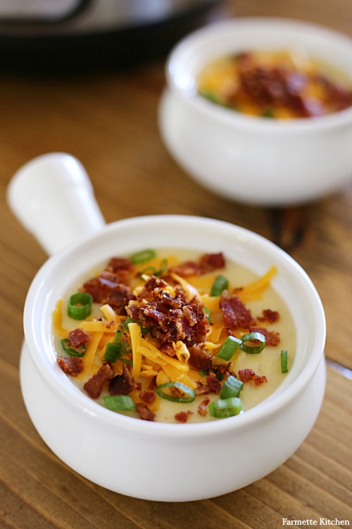 white crock filled with potato soup with toppings