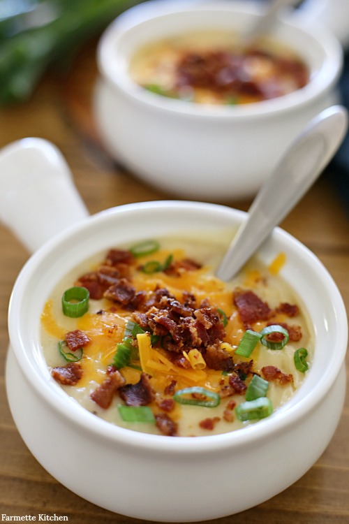 white crock filled with potato soup and toppings with a spoon