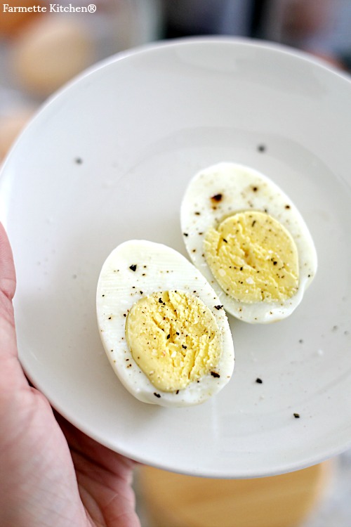 hard boiled egg halved on a plate with salt and pepper