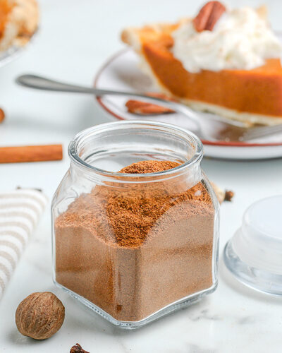 pumpkin pie spices in a jar with cinnamon sticks and whole cloves scattered around