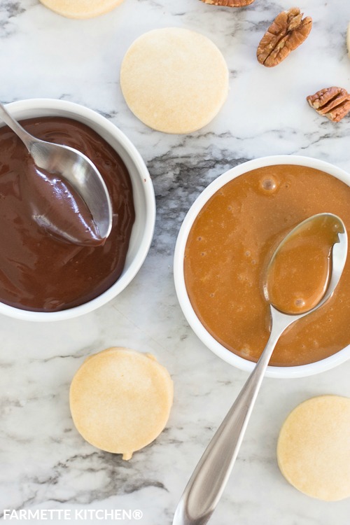 a bowl of melted chocolate and melted caramel next to shortbread cookies
