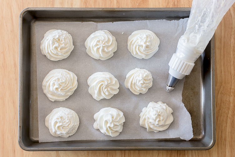 whipped cream piped onto a baking sheet