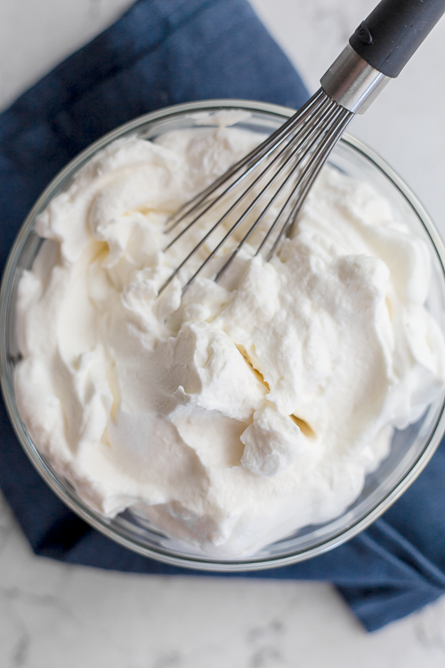 big bowl of homemade whipped cream with a whisk in it