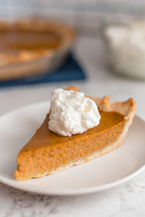 a piece of pumpkin pie with a big dollop of whipped cream