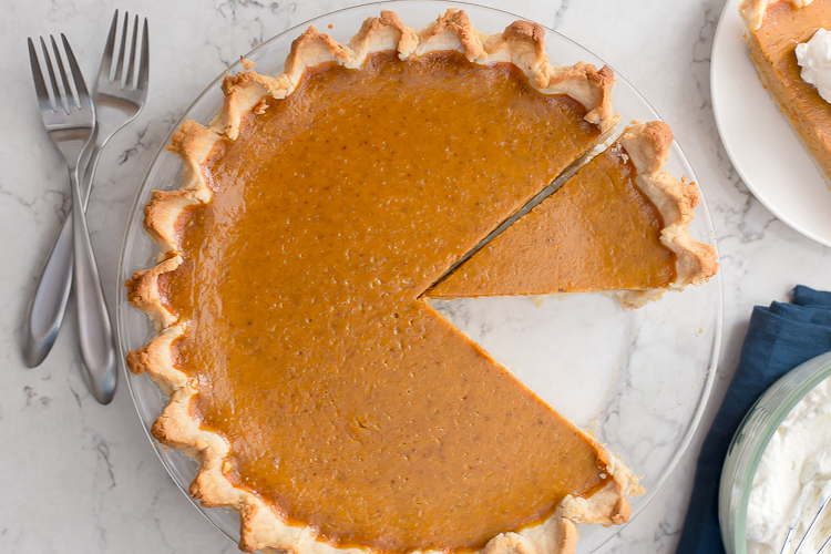 Pumpkin pie with a slice cut out and one slice removed