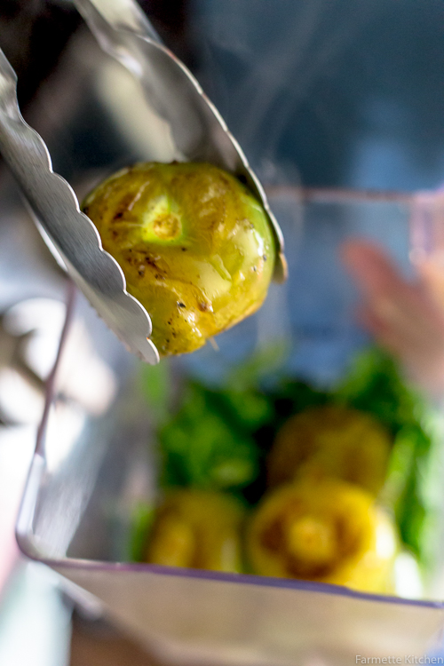 adding a roasted tomatillo to a blender jar