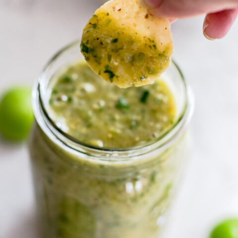 scooping salsa verde with a chip