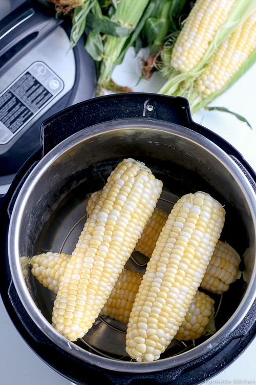 four ears of uncooked corn in a pressure cooker