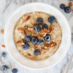 bowl of oatmeal with blueberries scattered around it