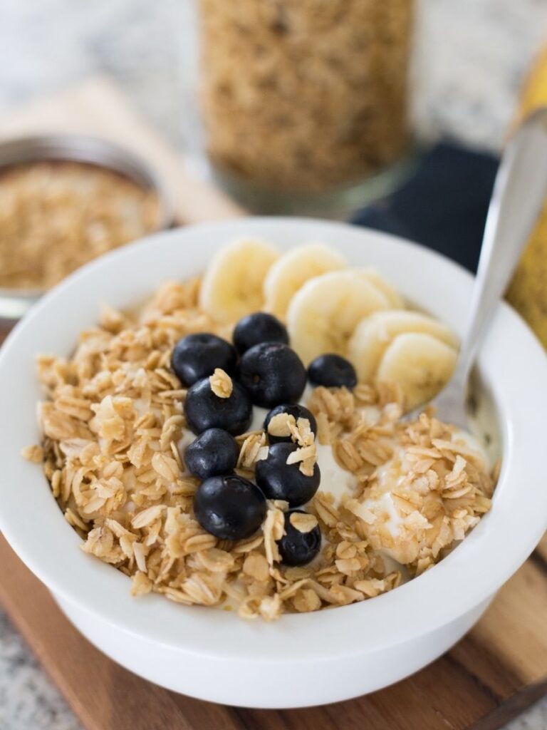 bowl of yogurt topped with granola, blueberries, and banana slices