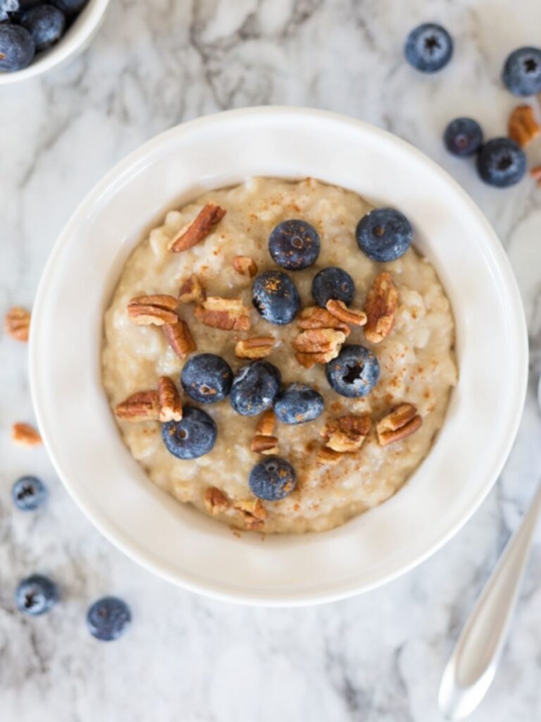 oatmeal in a white bowl topped with blueberries and pecans