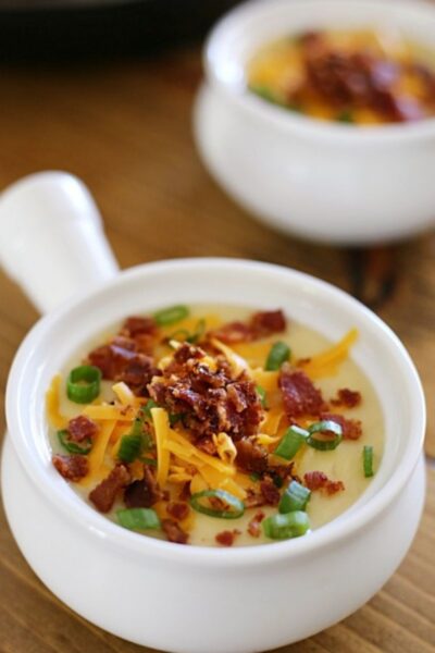 crock with potato soup topped with cheese, bacon, and onions