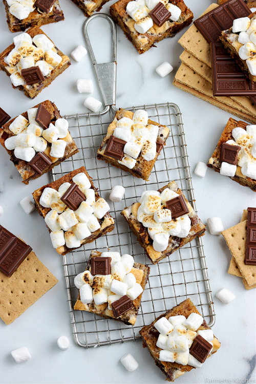 smores bars on a wire rack with ingredients scattered around