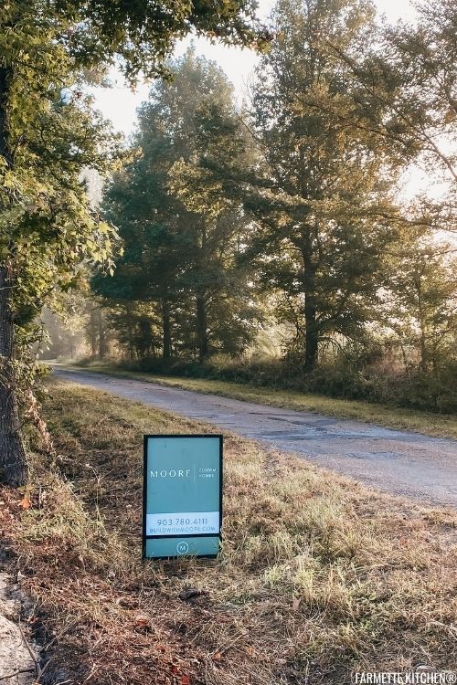 sign next to road with trees