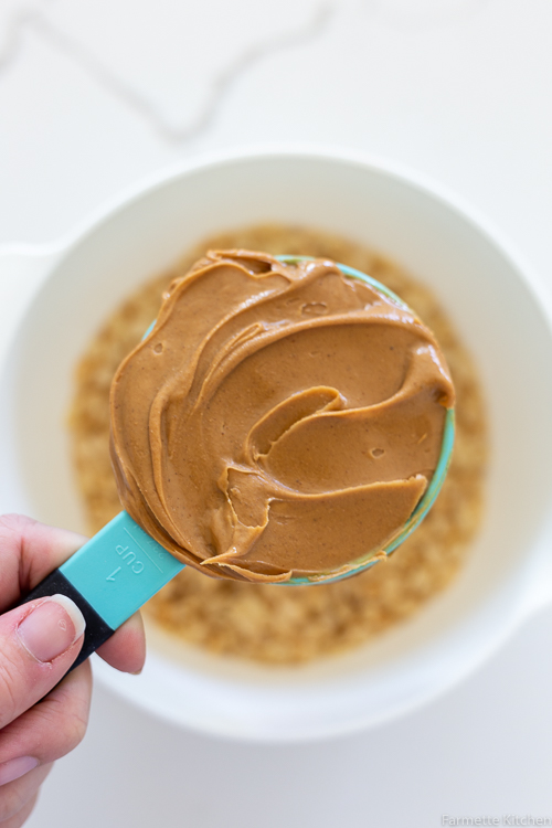 blue measuring cup full of creamy peanut butter