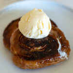 two honey buns on a plate topped with ice cream