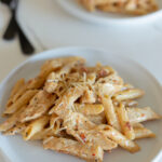close up of creamy tuscan chicken pasta on a white plate